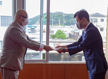 picture of donation ceremony, handing donation from Mr. Oka to Mr. Hori