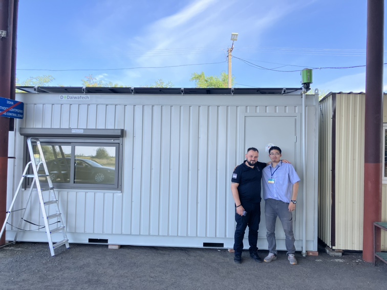 photo of Ukrainian engineer and Daiwatech engineer standing in front of the Daiwatech solar system houses donated to the Ukrainian government