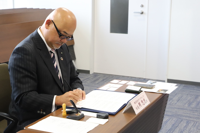 photo of President Oka, signing to the agreement